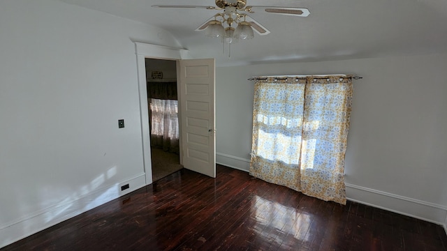 empty room with plenty of natural light, ceiling fan, and dark wood-type flooring