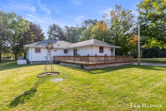 rear view of house featuring a lawn and a deck