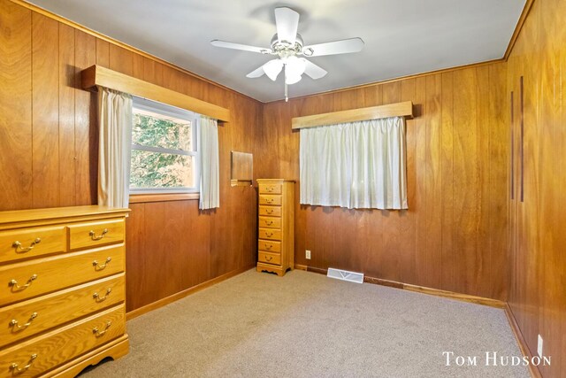 unfurnished bedroom featuring wood walls, ceiling fan, and light carpet