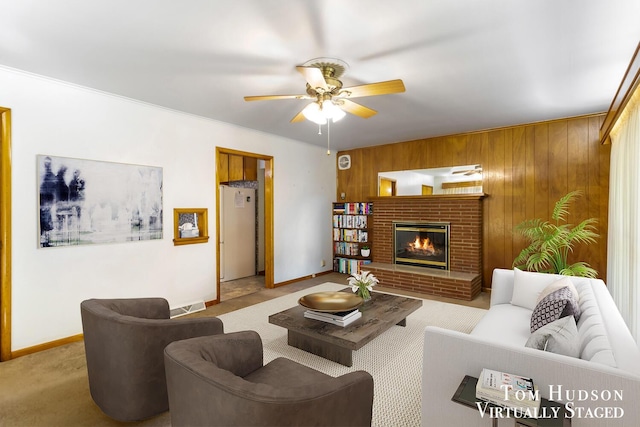 carpeted living room featuring a brick fireplace, ceiling fan, ornamental molding, and wood walls