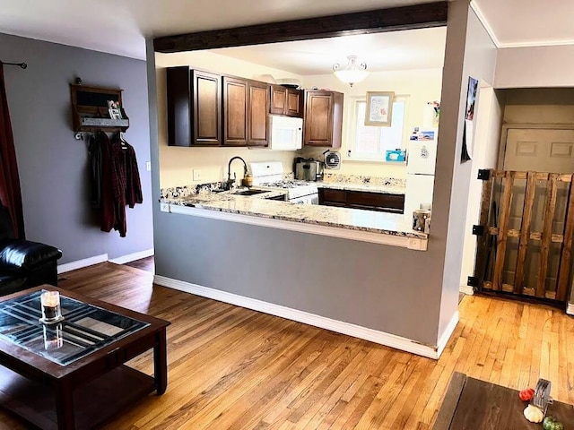 kitchen with light stone counters, white appliances, sink, beam ceiling, and light hardwood / wood-style flooring