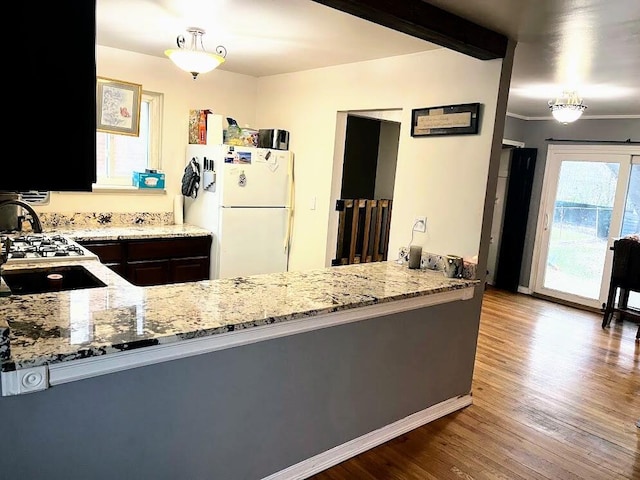 kitchen with sink, light stone counters, hardwood / wood-style floors, white fridge, and pendant lighting