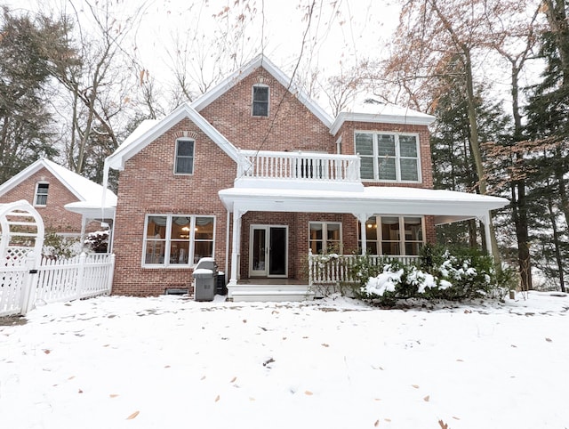 snow covered house with a balcony and covered porch