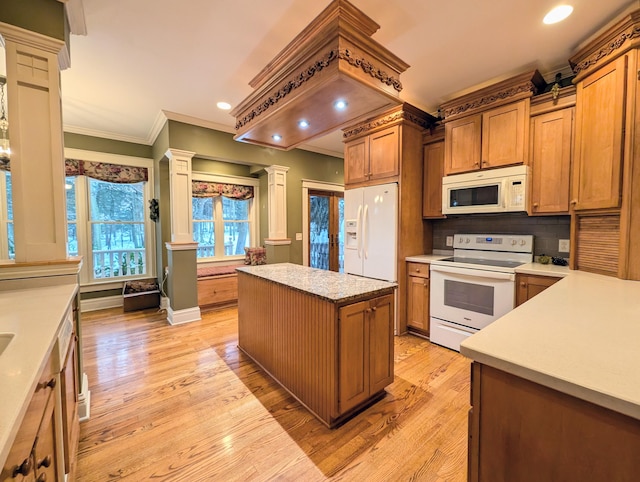 kitchen with light hardwood / wood-style floors, a center island, white appliances, and decorative columns