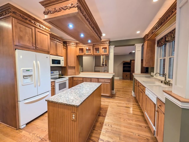 kitchen with sink, light hardwood / wood-style flooring, kitchen peninsula, white appliances, and a kitchen island