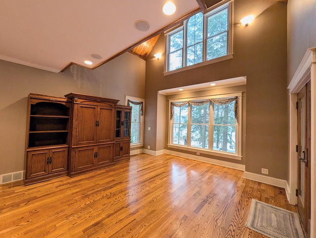 unfurnished living room with plenty of natural light, high vaulted ceiling, and light wood-type flooring