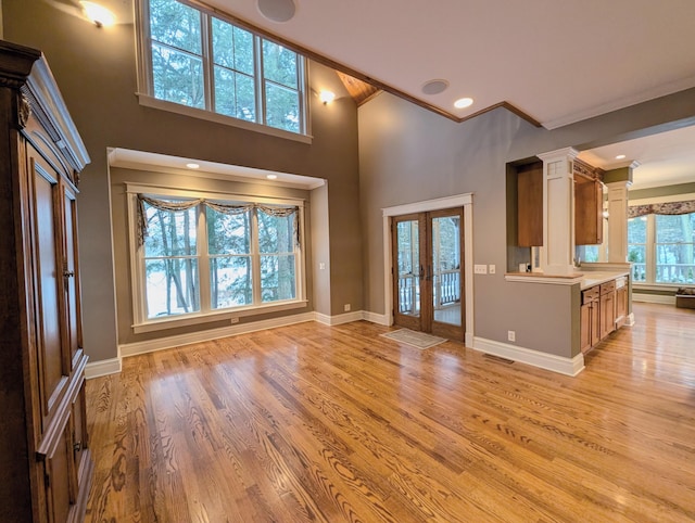 unfurnished living room featuring plenty of natural light, french doors, and light wood-type flooring