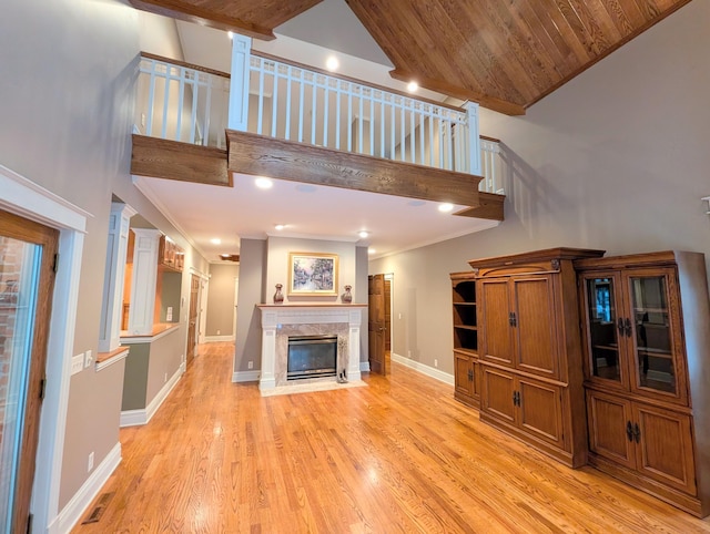 unfurnished living room with a fireplace, high vaulted ceiling, wood ceiling, and light wood-type flooring