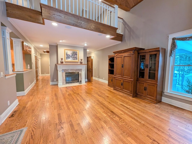 unfurnished living room with crown molding, a fireplace, and light wood-type flooring