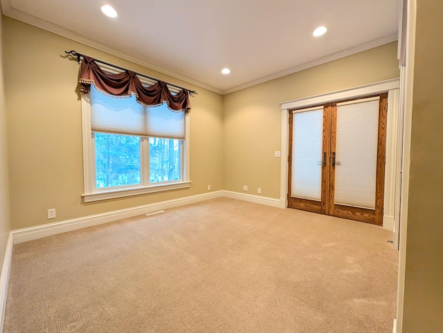 carpeted empty room featuring crown molding and french doors