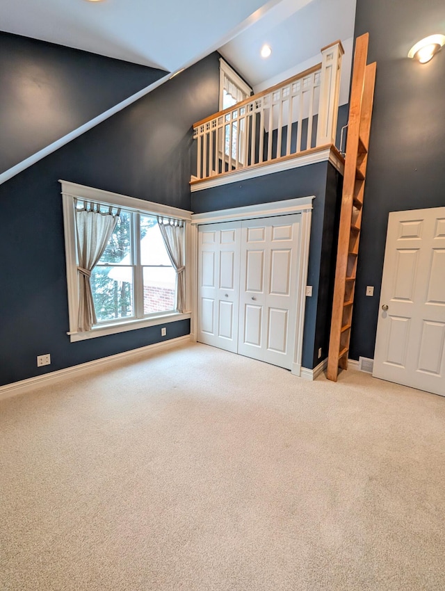 unfurnished living room with carpet flooring and a towering ceiling