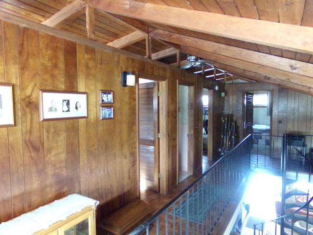 corridor with wooden ceiling, vaulted ceiling with beams, and wooden walls