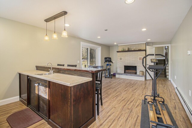 7293 M-116, Ludington, MI 49431 - kitchen featuring light wood finished floors, a baseboard radiator, a peninsula, a sink, and dark brown cabinetry