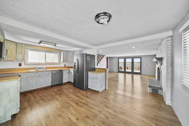 kitchen with sink, a brick fireplace, a textured ceiling, wood-type flooring, and stainless steel appliances