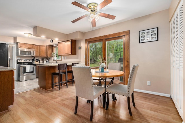 dining room with light wood-type flooring, ceiling fan, and sink