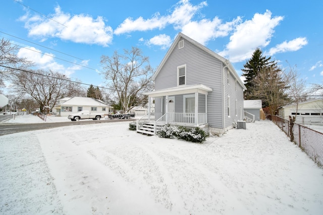 snow covered back of property featuring covered porch and central air condition unit