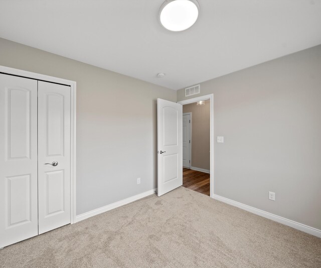 unfurnished bedroom featuring light colored carpet and a closet