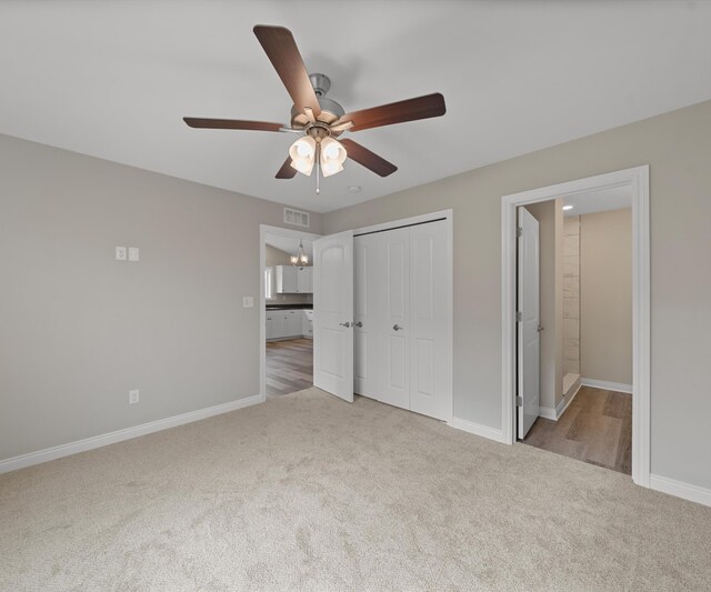 unfurnished bedroom with ensuite bath, ceiling fan, a closet, and light colored carpet