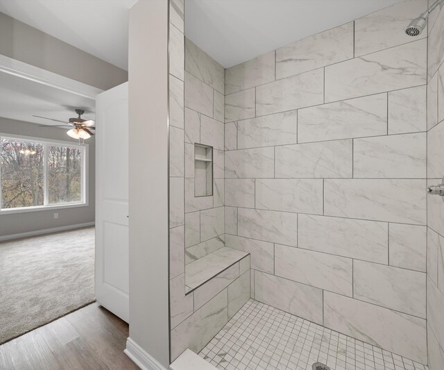 bathroom with hardwood / wood-style floors, ceiling fan, and a tile shower