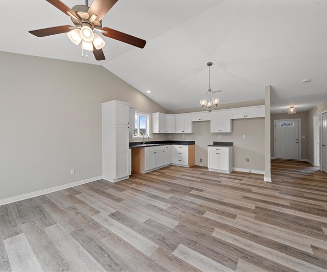 kitchen with ceiling fan with notable chandelier, sink, white cabinets, light hardwood / wood-style floors, and lofted ceiling