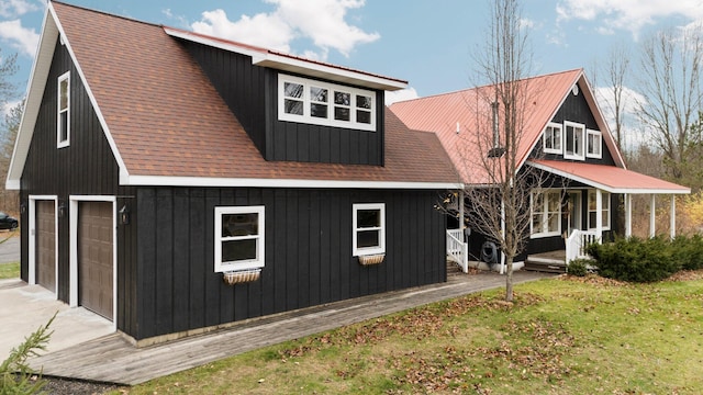 rear view of property featuring a porch, a garage, and a lawn