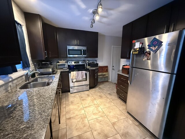 kitchen with stone counters, sink, backsplash, light tile patterned flooring, and appliances with stainless steel finishes