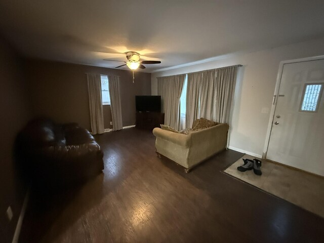 living room with ceiling fan and dark wood-type flooring