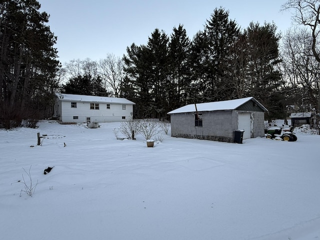 yard layered in snow with an outbuilding and a garage