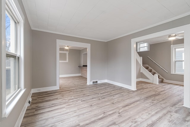 empty room with light hardwood / wood-style flooring, plenty of natural light, and ornamental molding