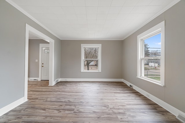 empty room with light hardwood / wood-style floors and crown molding