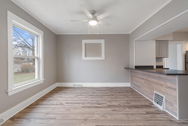 interior space with a wealth of natural light, crown molding, ceiling fan, and light hardwood / wood-style floors