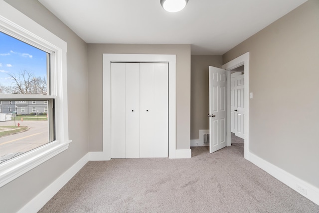 unfurnished bedroom featuring a closet and light colored carpet