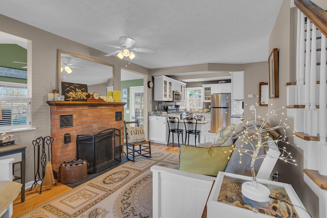 living room featuring a fireplace, a healthy amount of sunlight, light hardwood / wood-style floors, and a textured ceiling