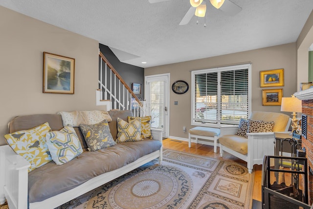 living room featuring ceiling fan, light hardwood / wood-style flooring, and a textured ceiling