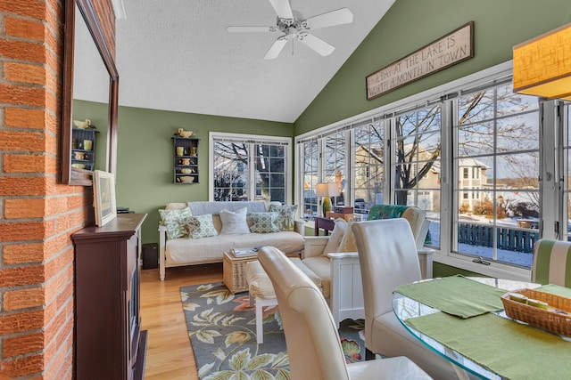 living room with a textured ceiling, light hardwood / wood-style floors, ceiling fan, and lofted ceiling