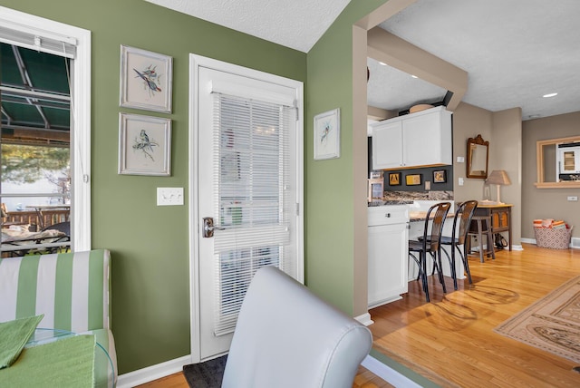 interior space with light wood-type flooring, white cabinetry, a textured ceiling, and built in desk