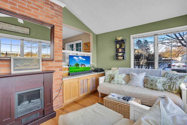 living room with a textured ceiling, lofted ceiling, and light wood-type flooring