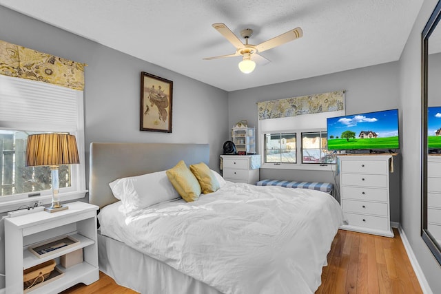 bedroom with multiple windows, ceiling fan, light hardwood / wood-style floors, and a textured ceiling