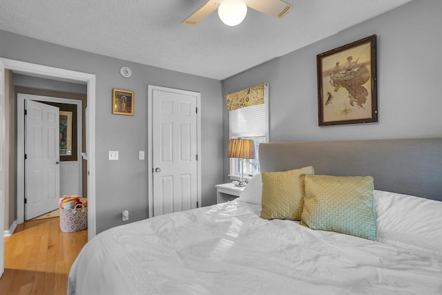 bedroom featuring ceiling fan, wood-type flooring, and a textured ceiling