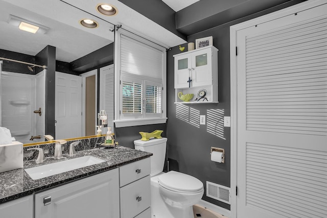 bathroom with vanity, a shower, toilet, and a textured ceiling