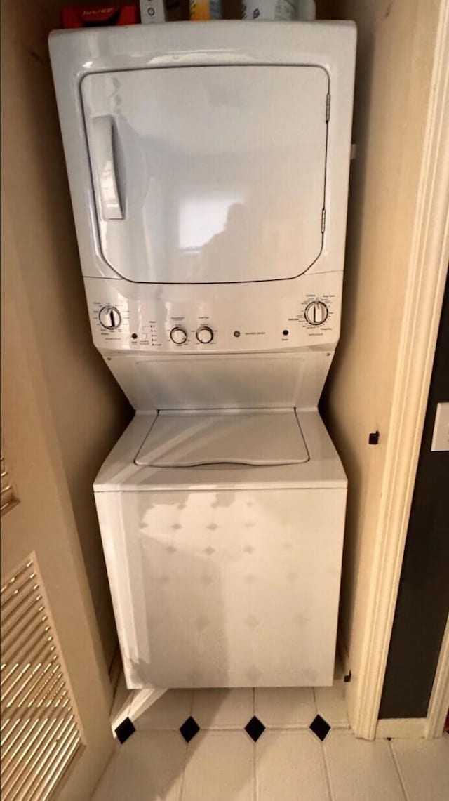 laundry room with tile patterned flooring and stacked washer / dryer