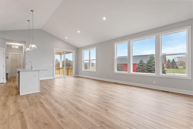 unfurnished living room featuring sink, vaulted ceiling, and light wood-type flooring