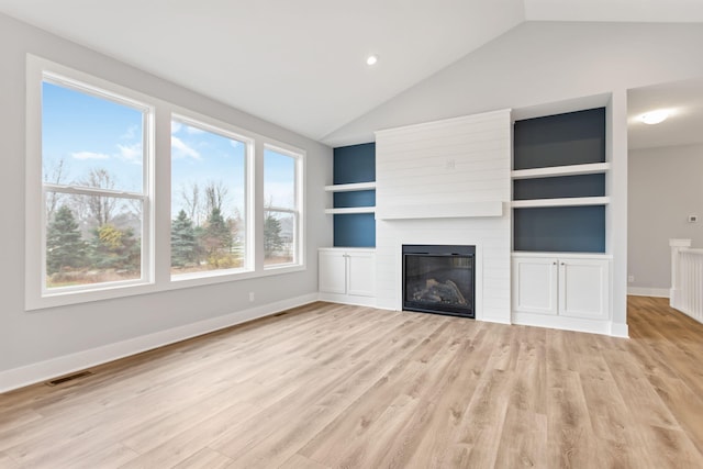 unfurnished living room featuring built in features, a large fireplace, light hardwood / wood-style flooring, and lofted ceiling