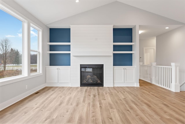 unfurnished living room featuring a large fireplace, light hardwood / wood-style floors, built in features, and vaulted ceiling