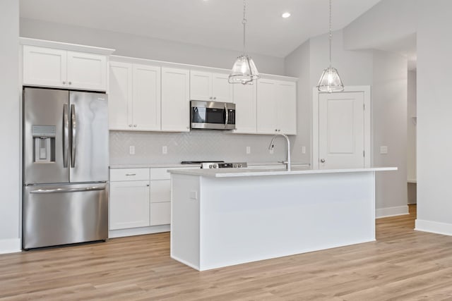 kitchen with a center island with sink, white cabinets, appliances with stainless steel finishes, decorative light fixtures, and light hardwood / wood-style floors