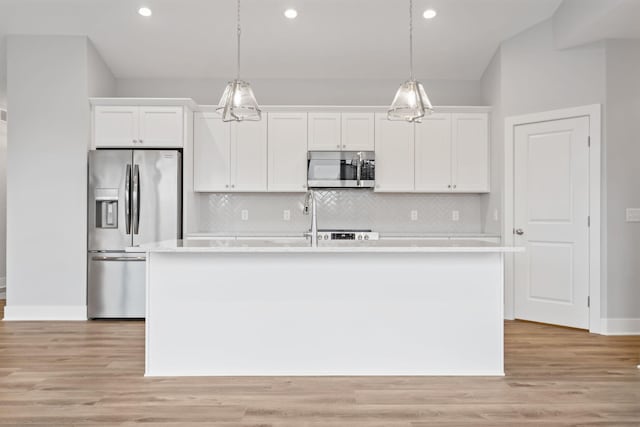 kitchen featuring white cabinetry, light hardwood / wood-style floors, decorative light fixtures, a kitchen island with sink, and appliances with stainless steel finishes