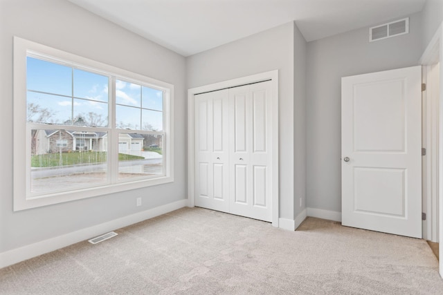 unfurnished bedroom featuring a closet and light colored carpet