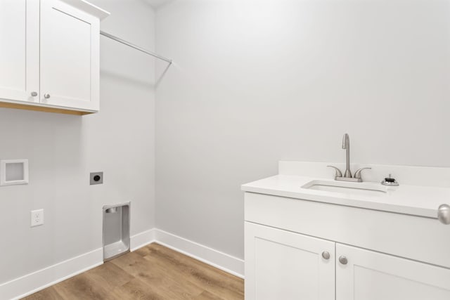 clothes washing area featuring electric dryer hookup, cabinets, sink, light hardwood / wood-style flooring, and washer hookup