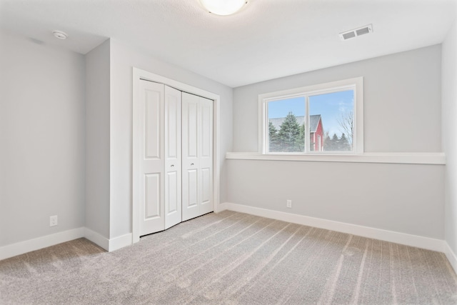 unfurnished bedroom featuring light carpet and a closet