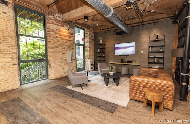 sitting room with brick wall, wooden ceiling, a high ceiling, and light hardwood / wood-style flooring